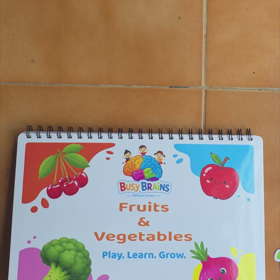 Toddler flipping through Busy Brains Fruits and Vegetables Activity Binder with Montessori learning pages