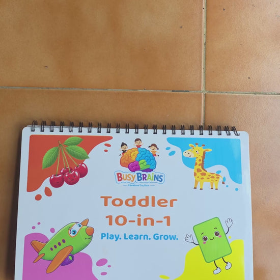Toddler flipping through Busy Brains Activity Binder with all in one Montessori learning pages