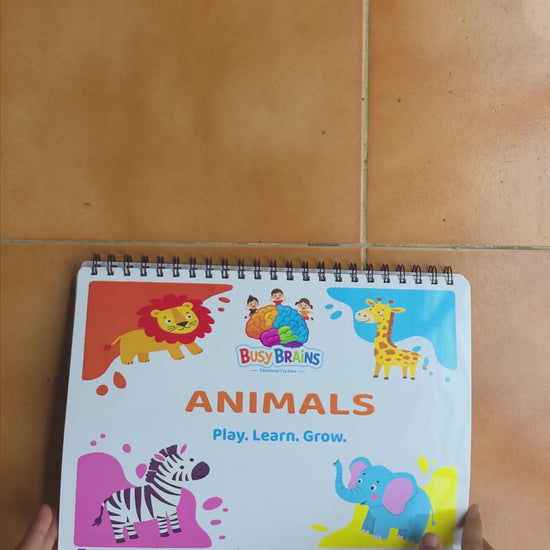Toddler flipping through Busy Brains Animals Activity Binder with sea animals Montessori learning pages