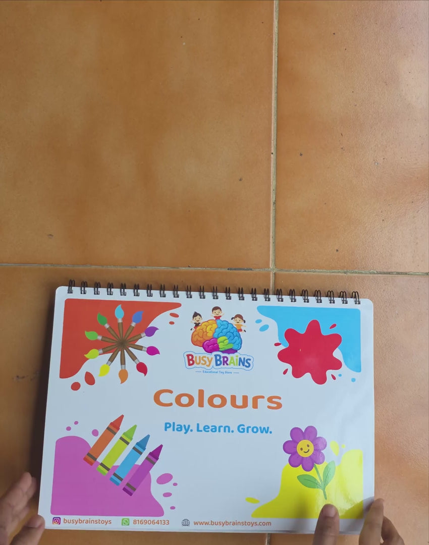 Toddler flipping through Busy Brains Colours Activity Binder with Montessori learning pages